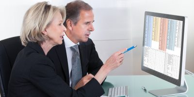 Happy,Mature,Businessman,And,Businesswoman,Looking,At,Graph,On,Computer