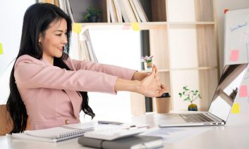 Positive,Asian,Woman,Finance,Is,Stretching,While,Working,After,A